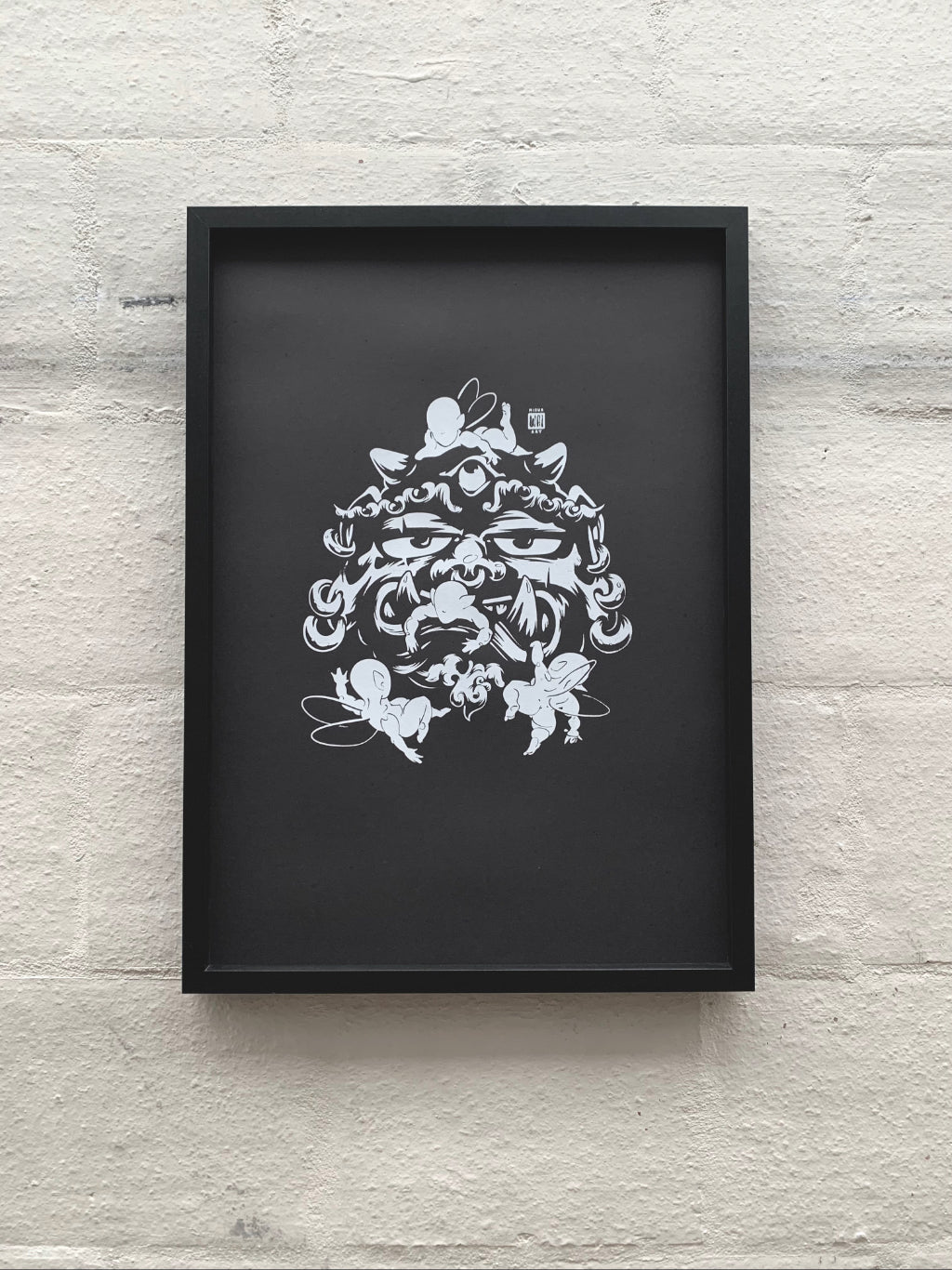 Asian mythical creature with earrings stuck around by faceless elves, printed with water-based white ink on black paper, framed in black and hung against white brick wall.