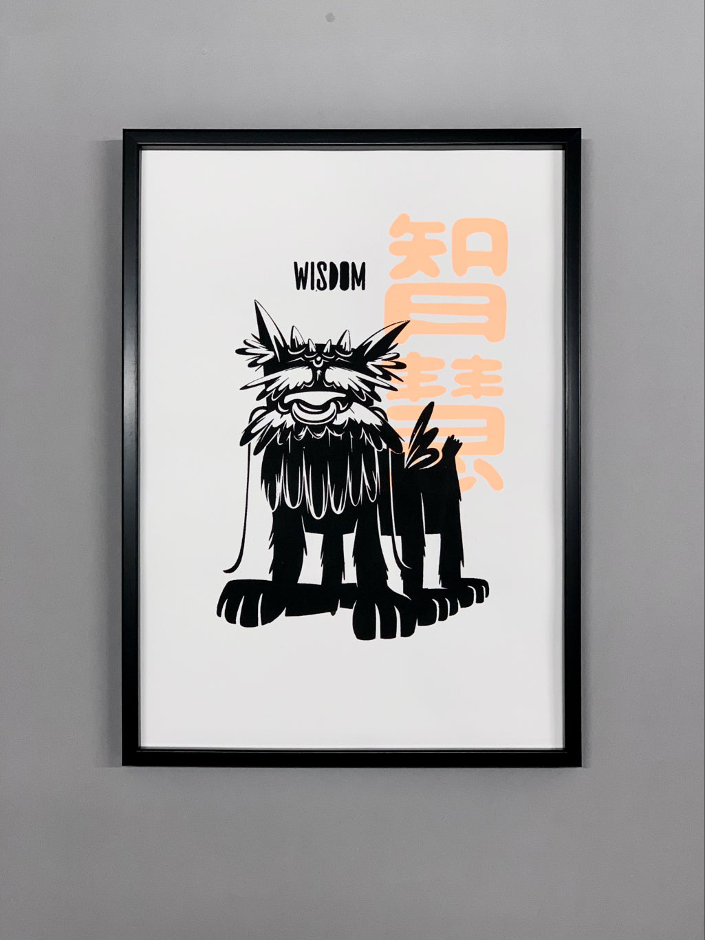 A dog-like mythical creature with text wisdom printed in black and Chinese character of wisdom is printed in fluorescent orange on white paper, framed in black hanging against grey wall.