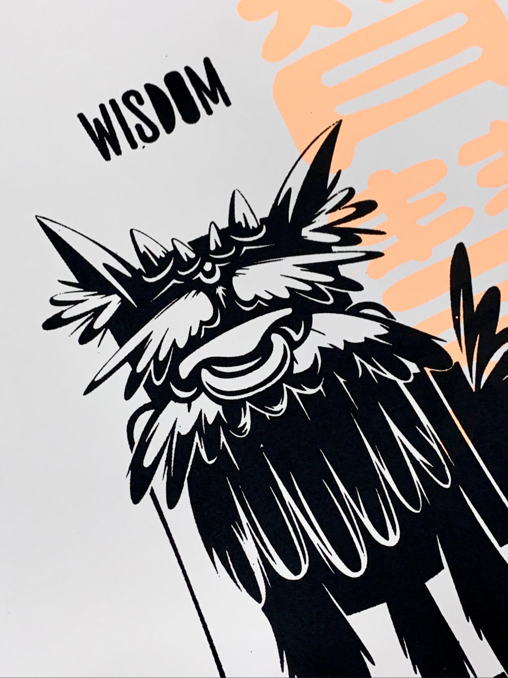 Close up of print with dog-like mythical creature with text wisdom in black and Chinese character of wisdom in fluorescent orange on white paper.